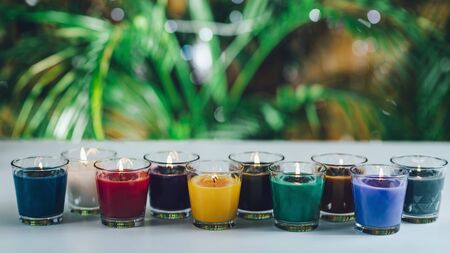 Scented Candles. Colorful flaming aromatic candles in a row on a white table with copy space for text.の写真素材