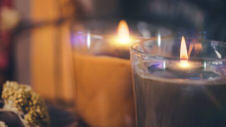 Scented brown and orange candles with presents, dried flowers and leaf decoration on table. Copy spaceの写真素材