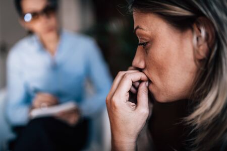 Woman with Anxiety Disorder, Biting Fingernails, Talking to Mental Health Professionalの写真素材