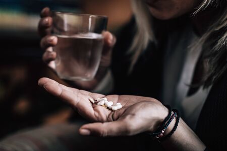 Antidepressant Medications - Gloomy image of a woman taking several pills to treat depressionの写真素材