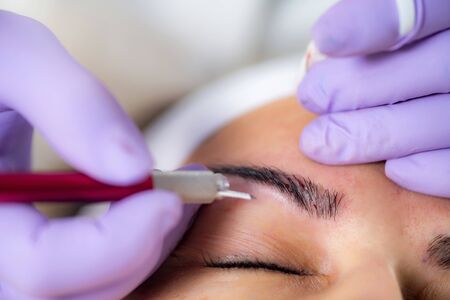 Beautician Microblading Eyebrows in Beauty Salon 