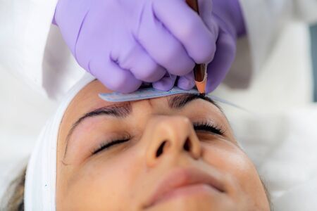 Beautician Addressing the Shape of the Brows Before Microblading.  Semi-Permanent Makeup