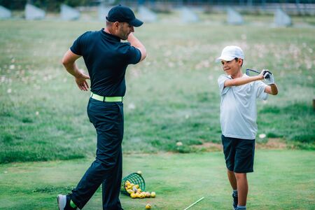 Golf Lessons. A golf Instructor and a boy practicing on a Golf Practice Range