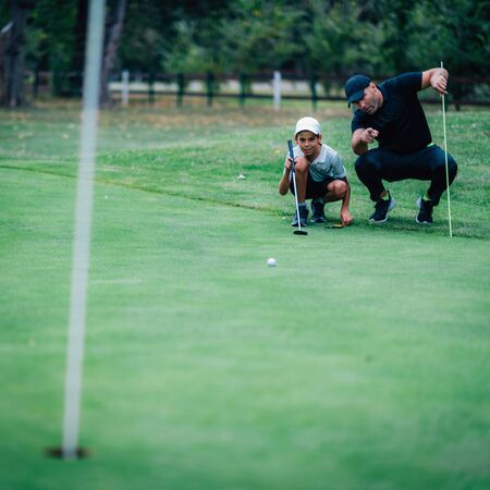Golf Putting Training. Golf Instructor with Young Boy Practicing on the Putting Greenの写真素材
