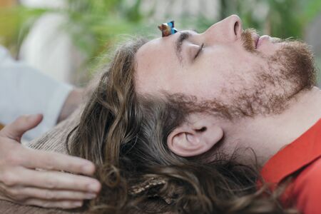 Young man lying on massage table and having Merkaba  crystal healing sessionの写真素材