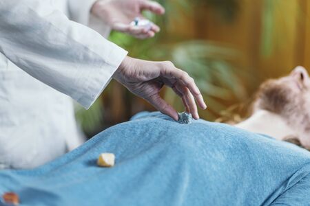 Crystal therapy.  Man lying on massage table, receiving healing with gems placed on body chakrasの写真素材