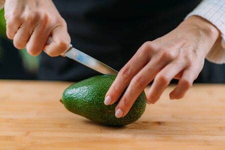 Cutting fresh, organic avocado, superfood rich in monosaturated fat, vitamins, minerals, fibers and phytonutrientsの写真素材
