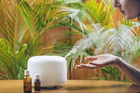 Woman Enjoying Aroma Therapy Steam Scent from Home Essential Oil Diffuser or Air Humidifier. Ultrasonic technology, increasing air humidity indoors for more comfortable living conditionsの写真素材