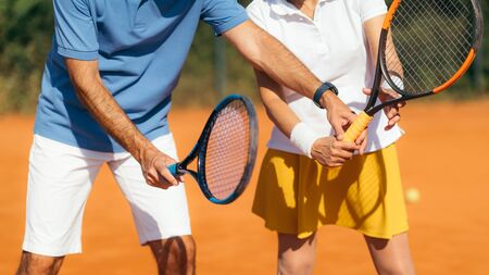 Tennis Instructor with Senior Woman on Clay Court. Woman having a Tennis Lesson.の写真素材