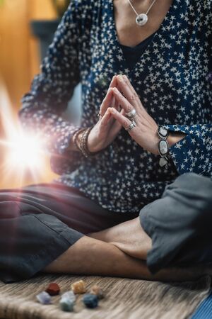 Mindful female Meditating at home in lotus position absorbing energy from energy from crystals.の写真素材