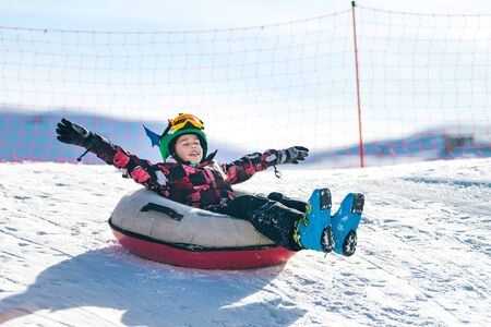 Child in Snow Tube Sledding Downhillの写真素材