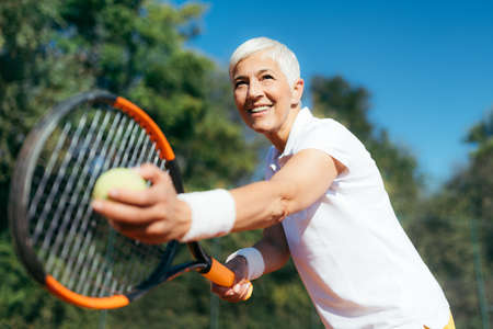Smiling Elderly Woman Playing Tennis as a Recreational Activityの写真素材