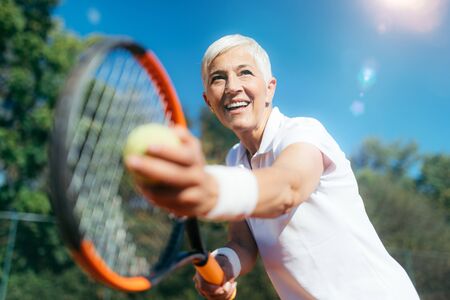 Smiling Elderly Woman Playing Tennis as a Recreational Activityの写真素材