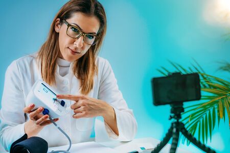 Telehealth â Medical doctor recording video instructions for patient and demonstrating how to measure blood sugarの写真素材