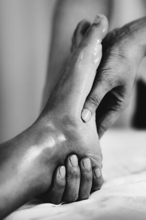 Physiotherapist massaging female patient with injured foot. Sports injury treatment.の写真素材
