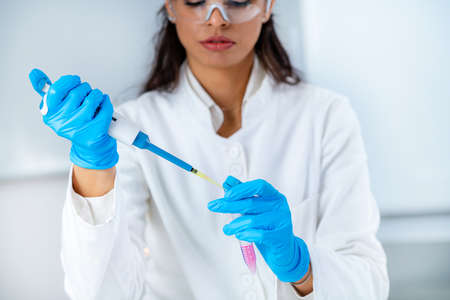 Student in White Coat, Working in Research Laboratory Using Micro Pipette and Test Tube