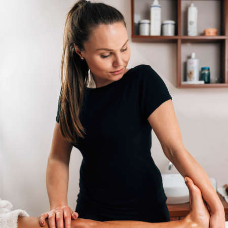 Foot reflexology massage. Female therapist massaging clientâ€™s foot at wellness salon
