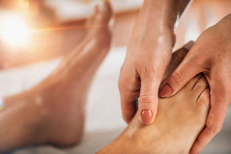 Reflexology or zone therapy practitioner applying pressure to meridian point on a female feelの写真素材