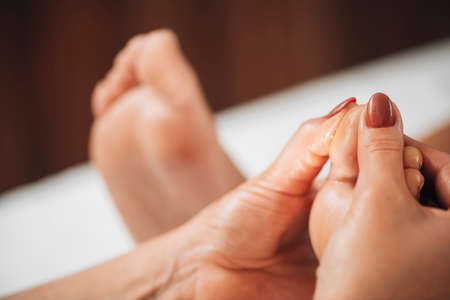 Reflexology or zone therapy practitioner applying pressure to meridian point on a female feelの写真素材