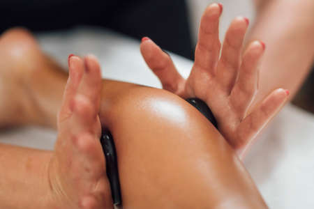 Hot Stone Foot Massage. Therapist relieving tension from clientâs feetの写真素材