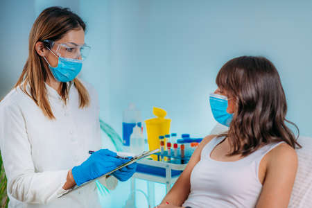 Nurse with Protective Mask Filling in Information Form. Blood Drawing and Analysis During Covid19 Coronavirus Crisisの写真素材