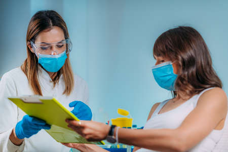 Nurse with Protective Mask Filling in Information Form. Blood Drawing and Analysis During Covid19...