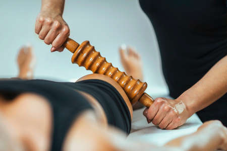 Rolling pin madero therapy massage. Female masseuse performing cellulite reduction treatment