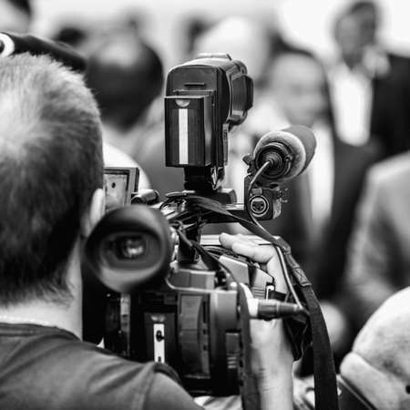 Camera operator working at a press conference outdoors. Journalists interviewing formal dressed...