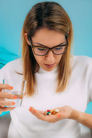 Supplementation. Woman holding a myriad of vitamin and mineral supplements in her hand.