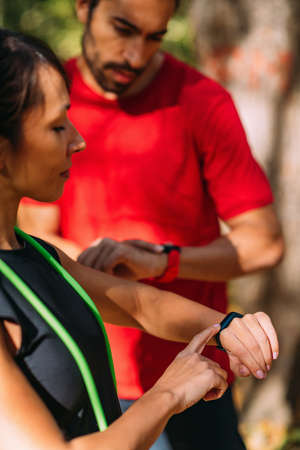 Young couple checking progress on their smart watches after outdoor training