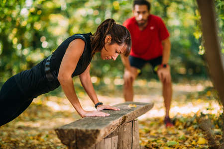 Woman doing push-ups in the park with personal trainerの写真素材