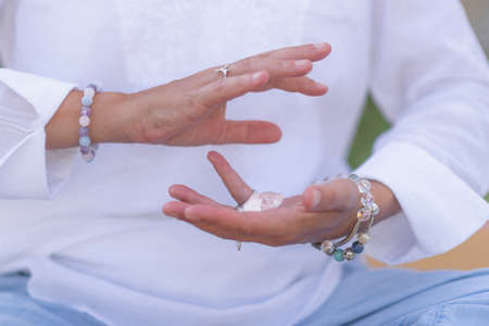 Female crystal healing therapist meditating, manifesting abundance with white selenite crystal. Energy workの写真素材