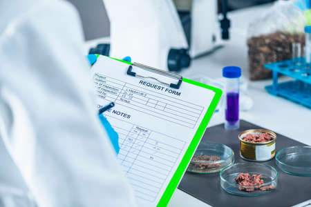 Pet Food Quality Control.  Laboratory Technician Making Notes for Pet Food Safety Test Close Up.