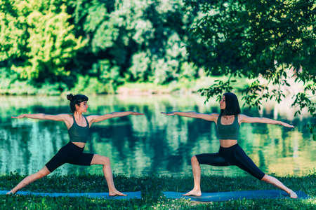 Yoga Women by The Lake. Warrior Poseの写真素材