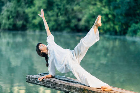 Yoga by the Lake â€“ Young woman doing yoga exercise plank star pose