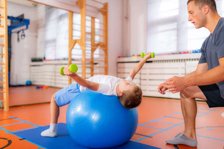 Pectoral or chest muscle exercises for children with a fitness ballの写真素材