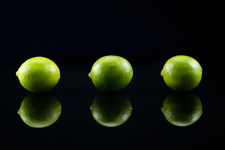 Limes on black background with reflectionの写真素材