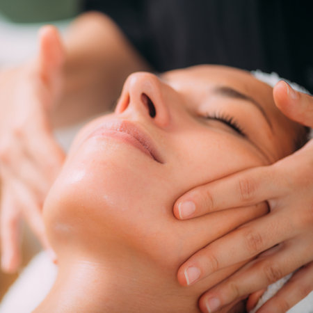 Woman Enjoying a Professional Ayurvedic Facial Massage with Therapeutic Essential Oilsの写真素材