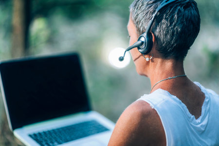 Remote work. Positive middle-aged woman working remotely, wearing a headset, talkingの写真素材