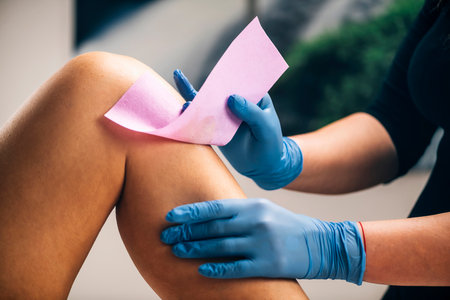 Waxing - Beautician Removing Unwanted Hair from Female Leg with Wax Strips in a Beauty Salonの写真素材