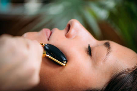 Face Roller. Woman Using Face Roller at Home.の写真素材