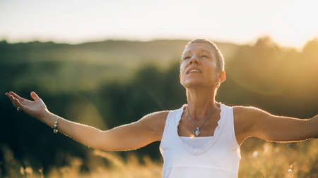 Positive Sunshine - Mindful Woman Enjoying Sunlight, Embracing the Positive Feeling created by sunshine, feeling connected with herselfの写真素材