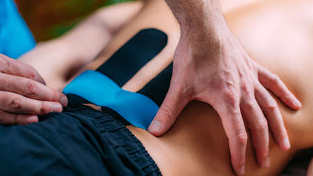 Kinesio Tape Application. Physical Therapist Placing Kinesio Tape on Patientâs Lower Backの写真素材