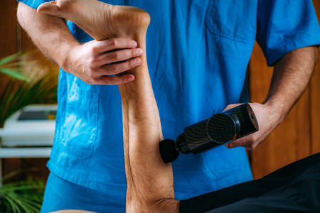 Therapist Treating Calf Injury on Athlete with Massage Gun