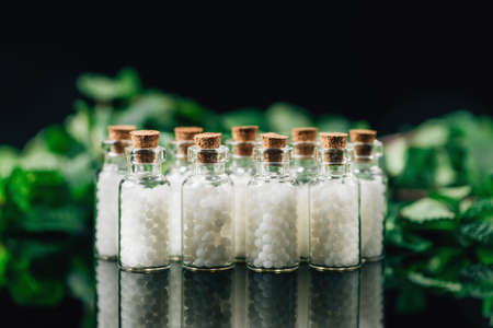Homeopathic Medicine - Homeopathy concept with homeopathic pills in bottles and green plants in the...