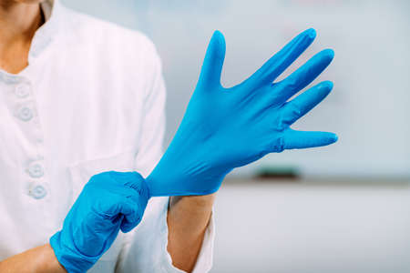 Lab technician putting on protective gloves. Laboratory safety equipment, hand protection.