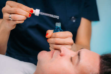 Cosmetician Applying Hyaluronic Acid Serum on Manâs Face in Beauty Salonの写真素材