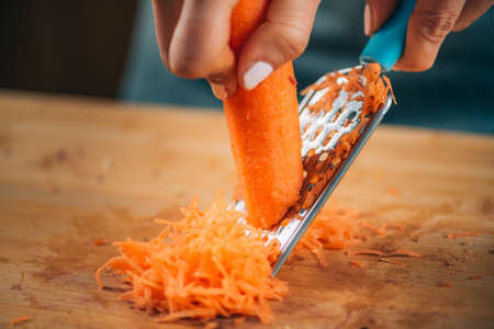 Fermenting vegetables. Woman shredding carrots, preparing them for fermentation.の写真素材