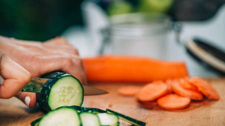 Fermentation process. Woman preparing vegetables for fermentation at home. Cutting cucumber and beets.の写真素材