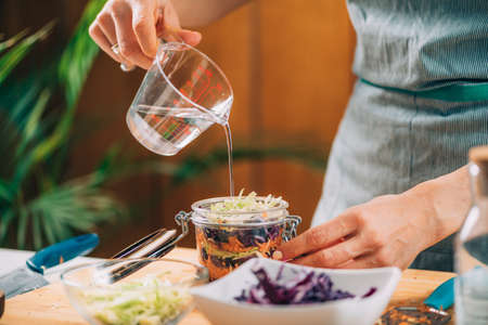 Homemade Fermented Vegetables.Homemade fermented vegetables. Woman pouring water in the jar with vegetables. Vegetable Fermentation Process.の写真素材